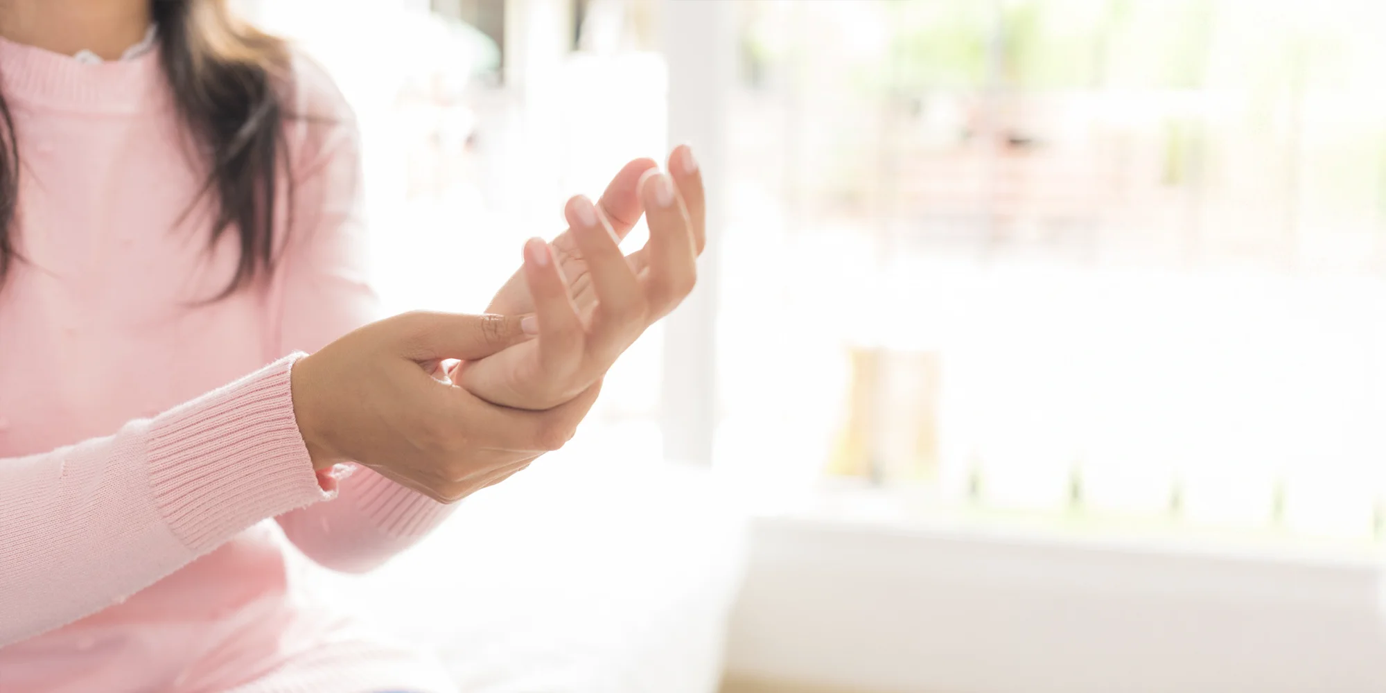 Close up of a woman in pink gripping wrist in pain